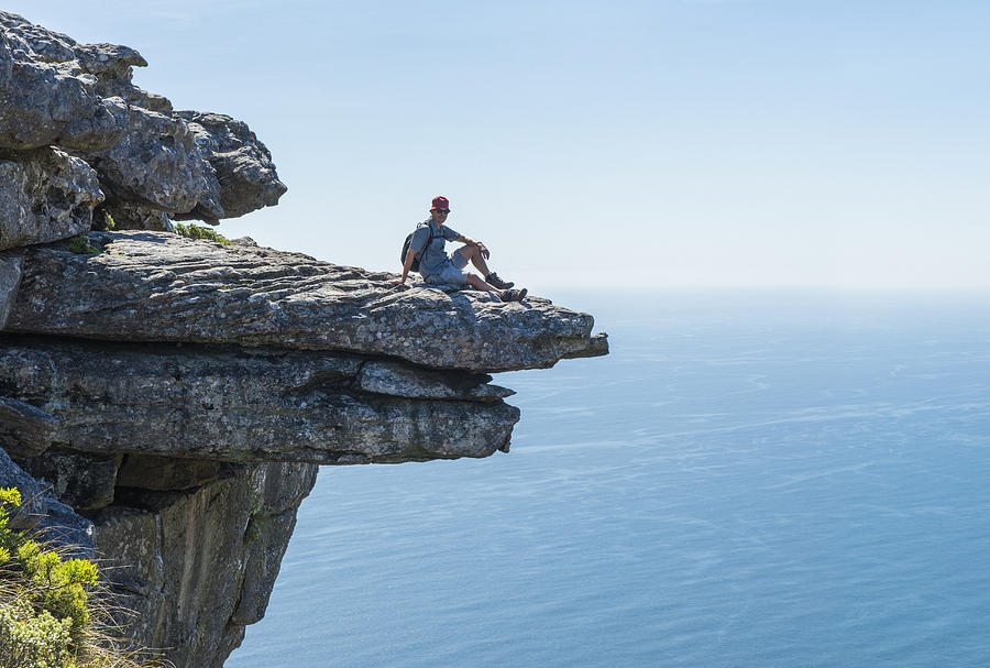 Man sitting on a rock ledge. Photograph by David Malan