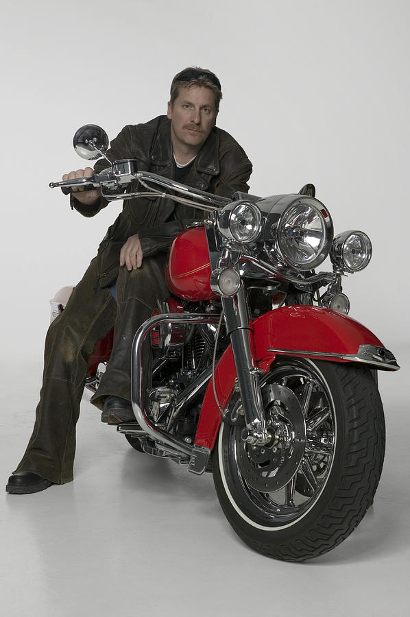 Man sitting on large red motorcycle, portrait Photograph by Photodisc
