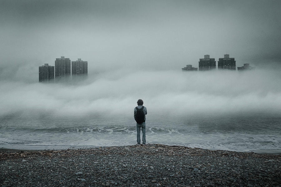 Man standing alone looking out to sea against moody sky during foggy weather Photograph by D3sign