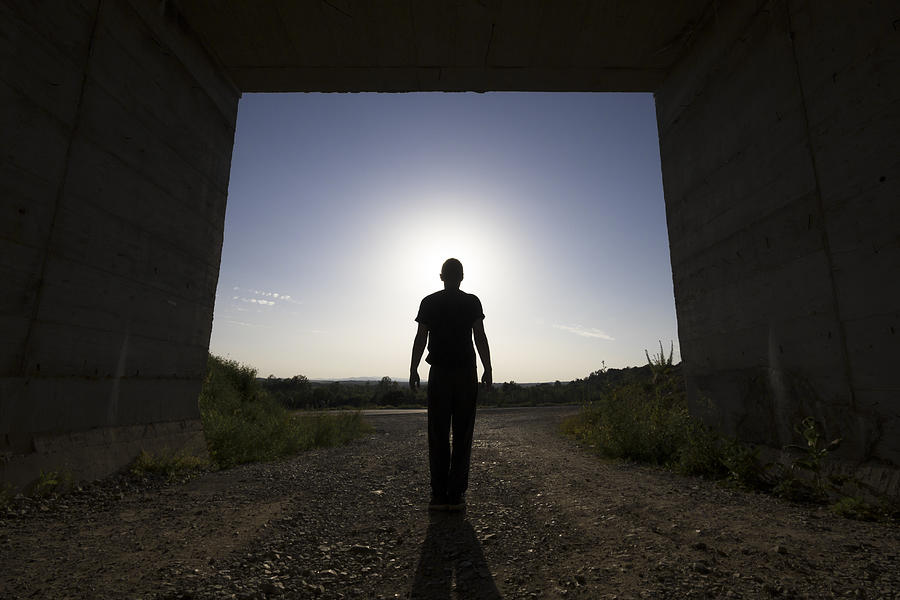 Man standing at large passage of concrete building, blocking sunlight Photograph by Marccophoto