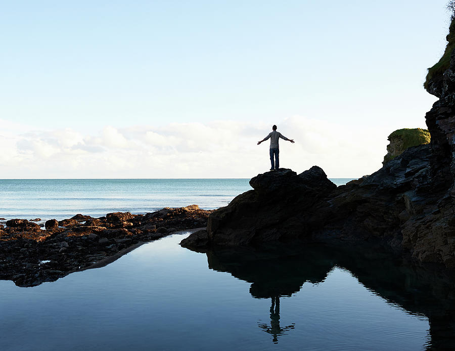 Man Standing By Rock Pool With Arms Out by Dougal Waters