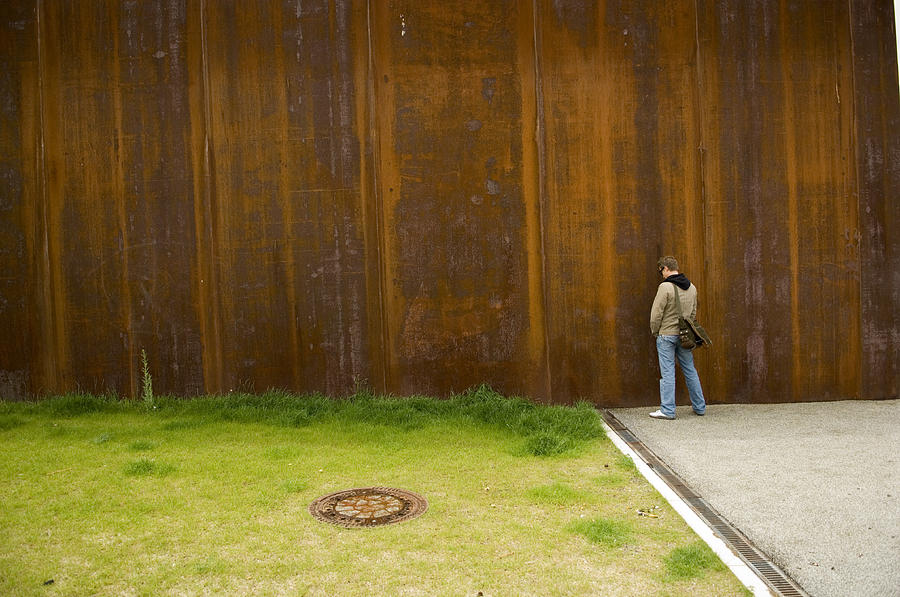 Man Urinating Outside on Rusty Wall Near Green Grass Photograph by Archives