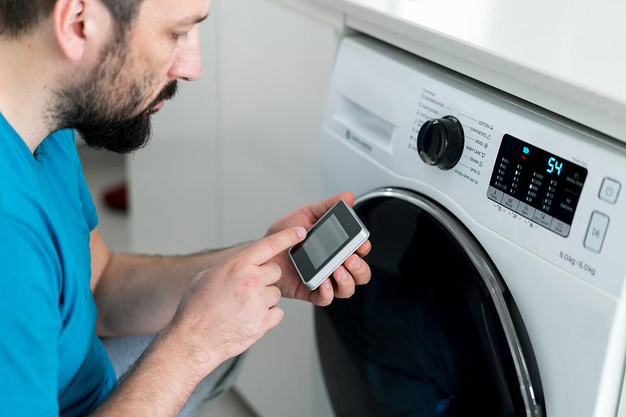 Man using digital device washing machine touch screen for smart home functions Photograph by Jasmin Merdan