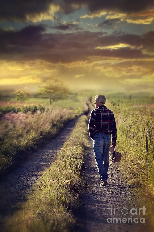 Man walking down a country road at sunset Photograph by Sandra Cunningham