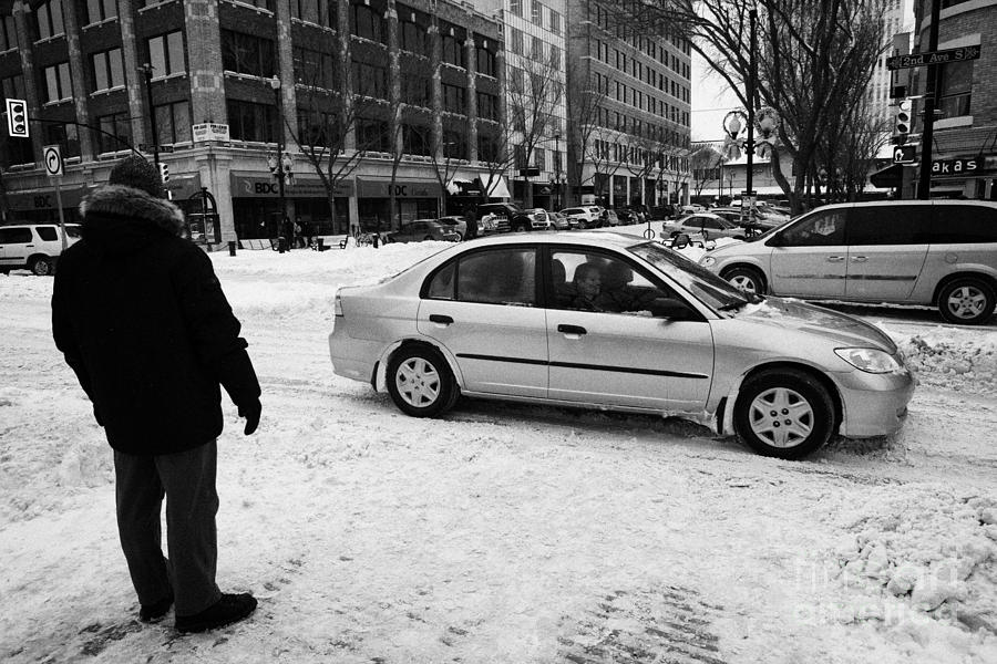 Winter Photograph - man watching car travelling along snow covered city streets in Saskatoon Saskatchewan Canada by Joe Fox