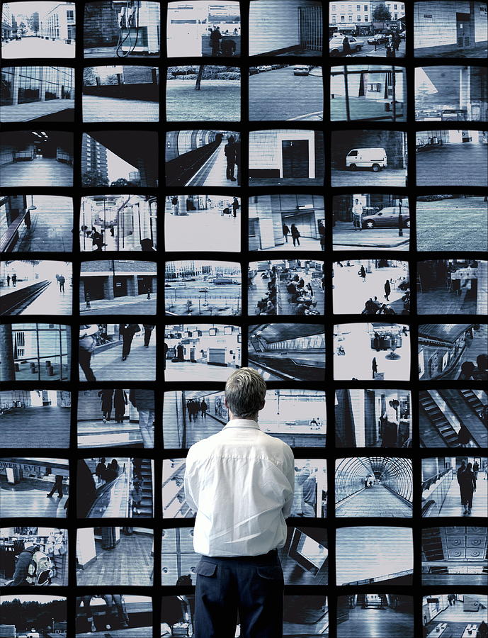 Man watching wall of surveillance screens Photograph by Robert Daly