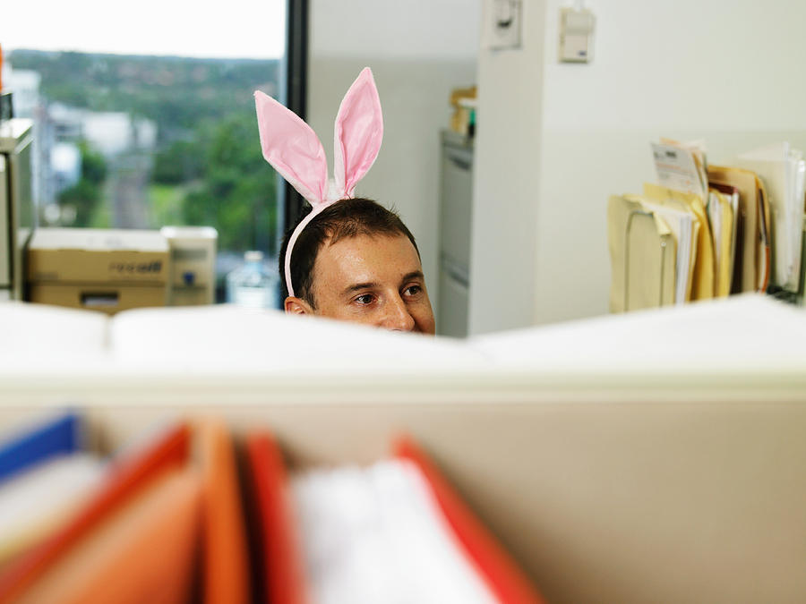 Man wearing bunny ears in office, desk divder in foreground Photograph by David Woolley