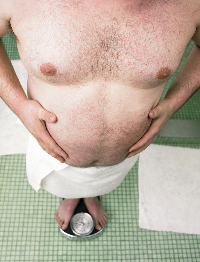 Man Weighing Himself on Bathroom Scales Photograph by Digital Vision.