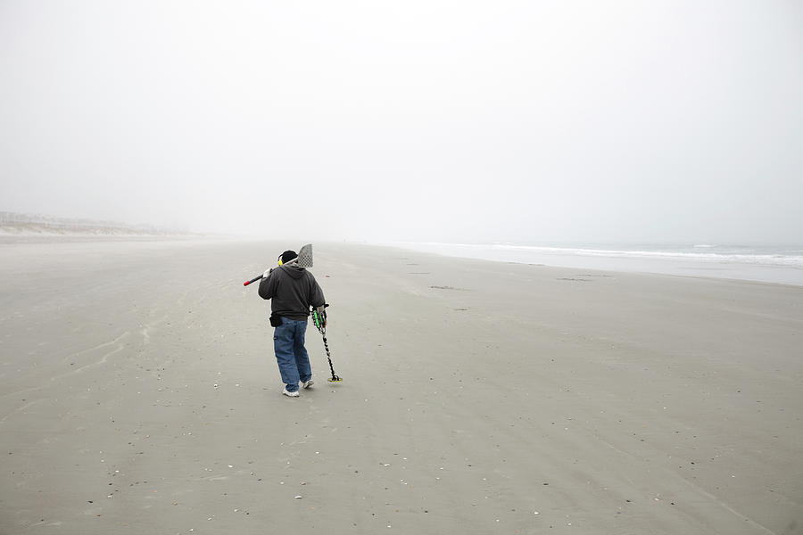 Beach Photograph - Man With A Metal Detector Searches by Eyeconic Images