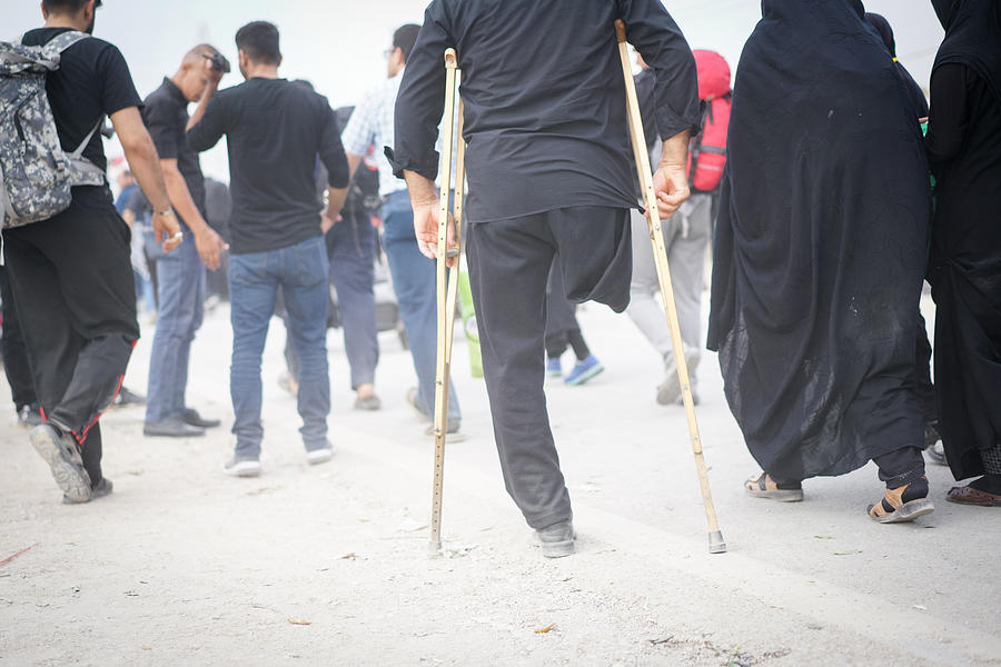 Man with amputee leg walking between people Photograph by Jasmin Merdan