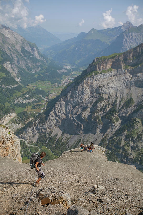 Man With Backpack Climbing Down Rope Photograph by Woods Wheatcroft ...