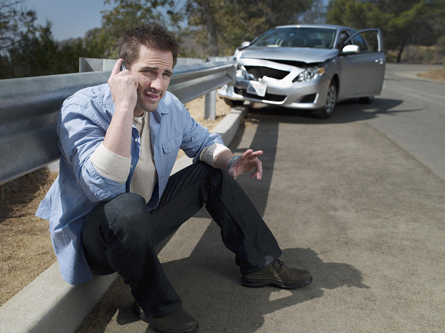 Man with crashed car calling for roadside assistance, Photograph by Chris Ryan