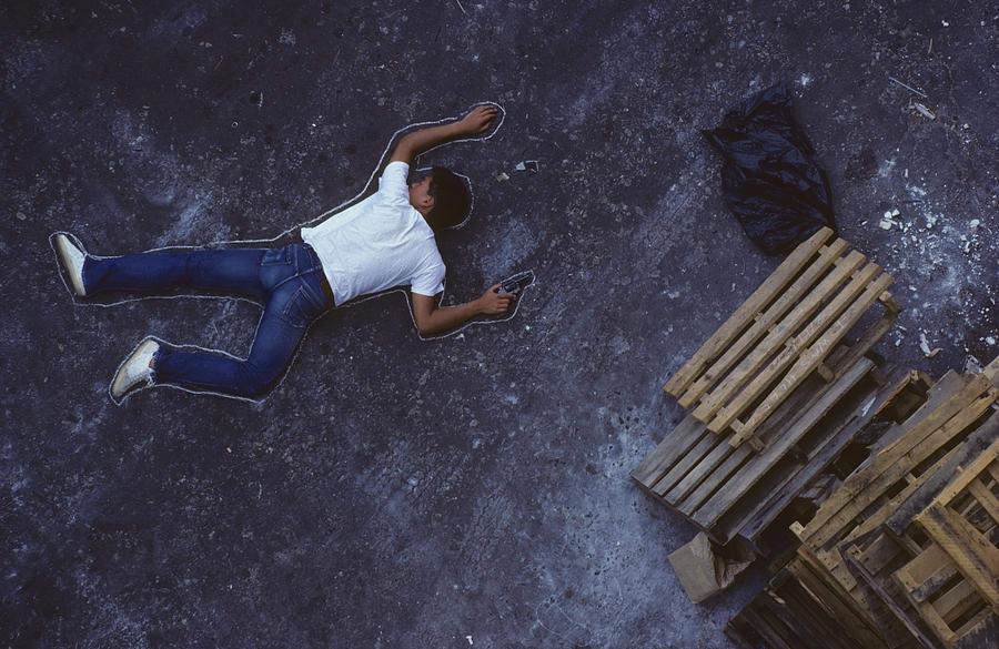 Man with gun lying on ground, chalk outline around him, elevated view Photograph by Stuart Gregory