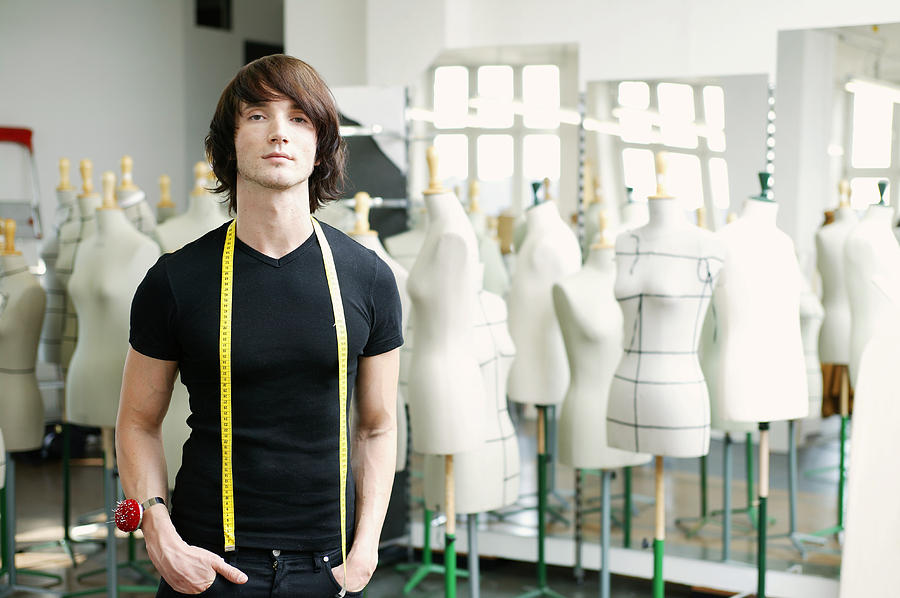 Man with tape measure round neck in fashion studio, portrait Photograph by Manchan