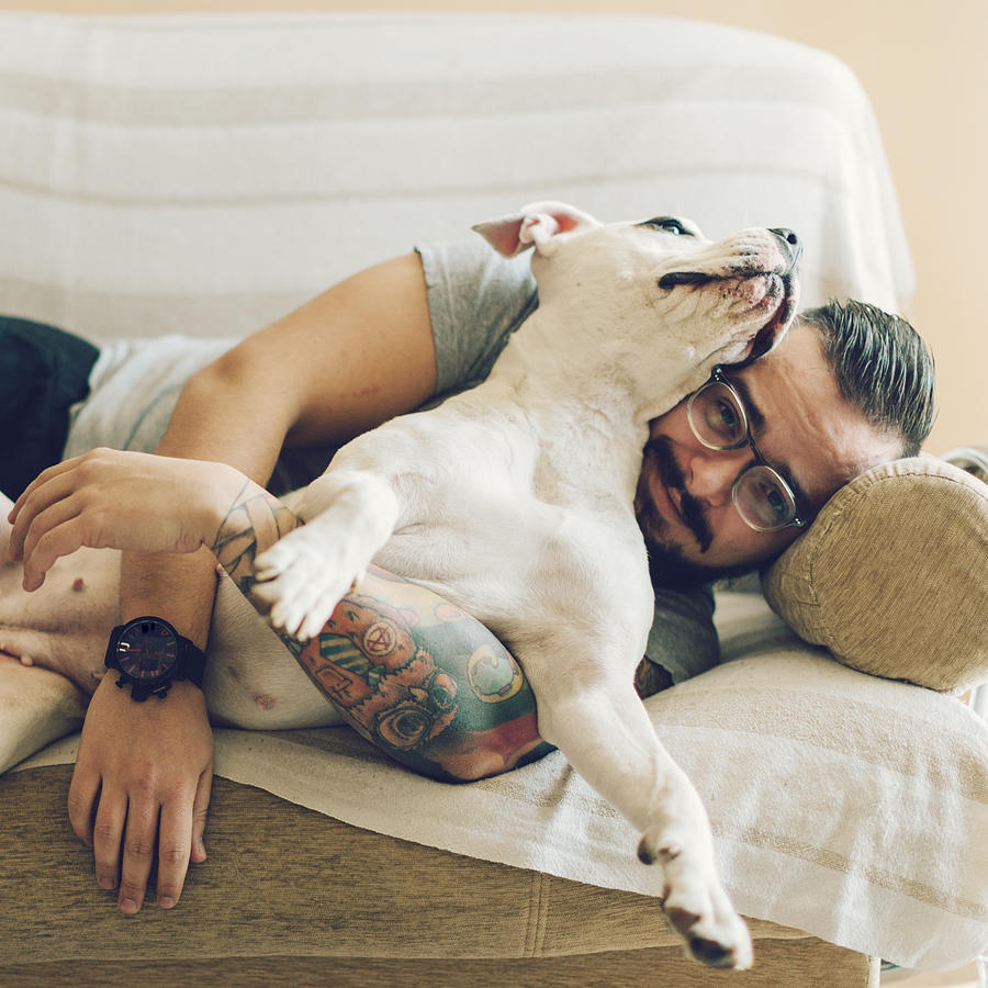 Man with tattoo embracing his dog. Photograph by Vgajic