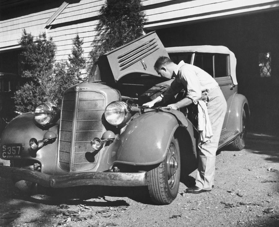 Black And White Photograph - Man Working On HIs Car by Underwood Archives