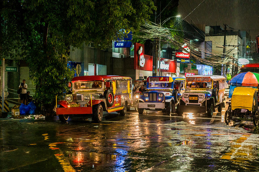Manila Malate area by night city street jeepneys pedicabs on the street on a rainy night Photograph by Holgs