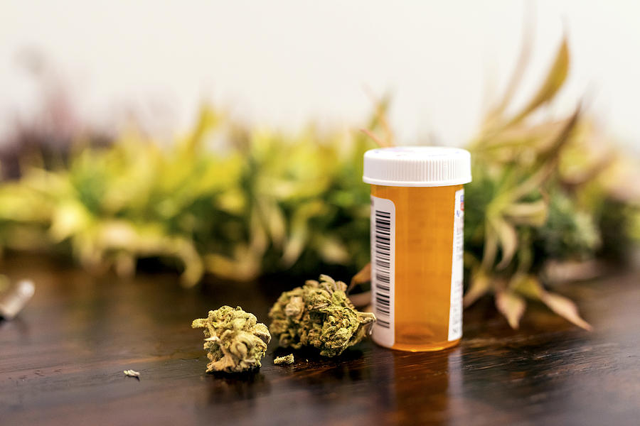 Marijuana buds sitting next to prescription medicine bottle Photograph by FatCamera