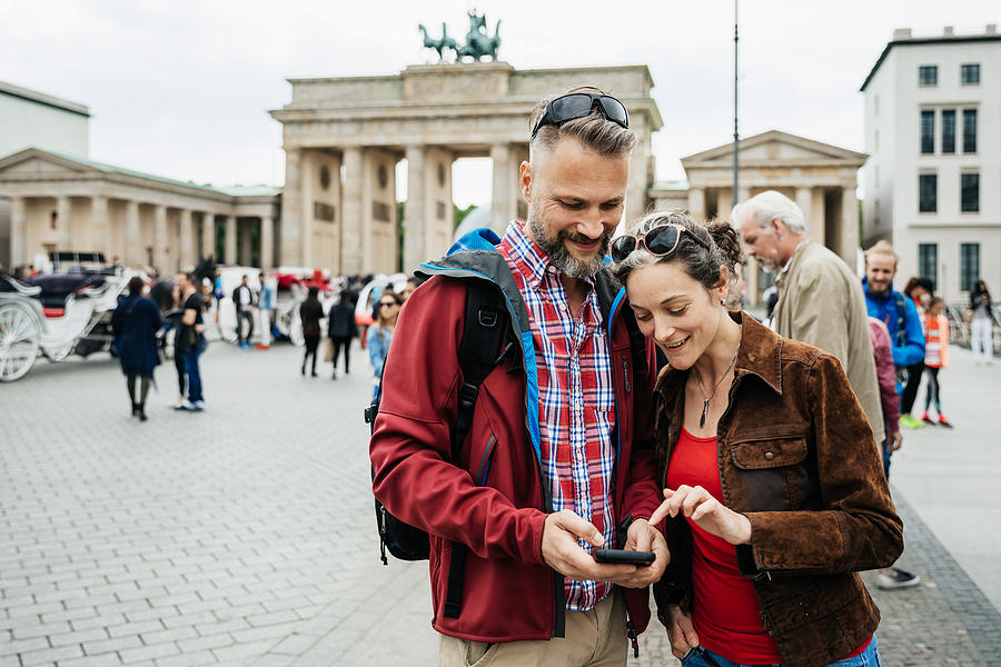 Mature Couple Looking Over Photos They Have Taken At Brandenburg Gate in Berlin Photograph by Hinterhaus Productions