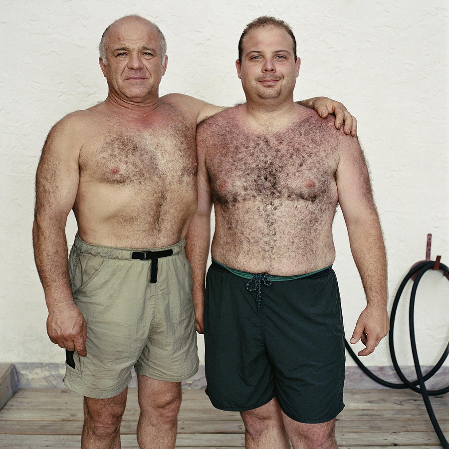 Mature father with arm around son, portrait Photograph by Stephen Mallon