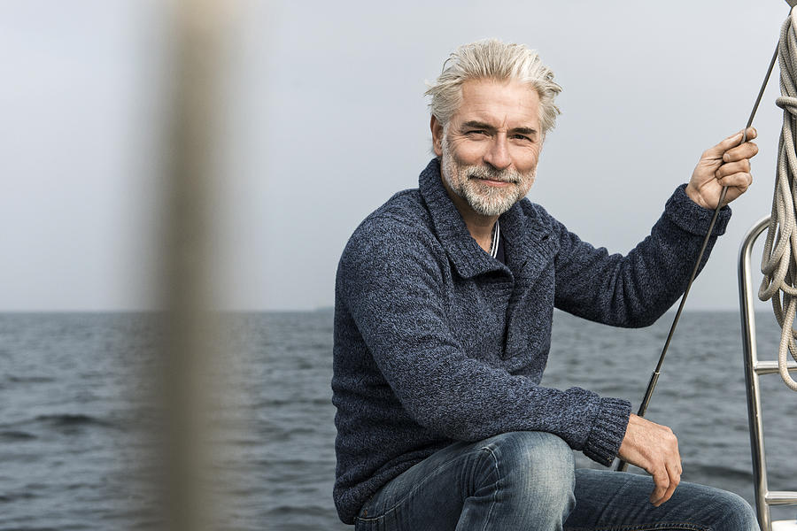 Mature grey haired man on board a sailing boat Photograph by Robin Skjoldborg