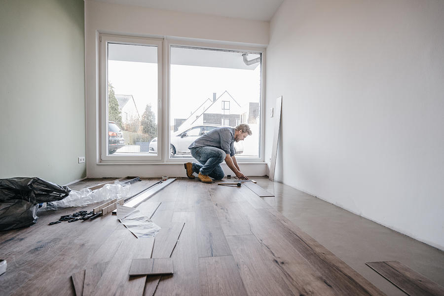 Mature man fitting flooring in new home Photograph by Westend61