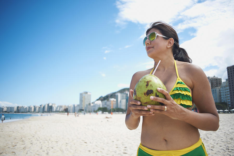 Mature woman drinking from coconut on Copacabana beach, Rio De Janeiro, Brazil Photograph by Peter Muller