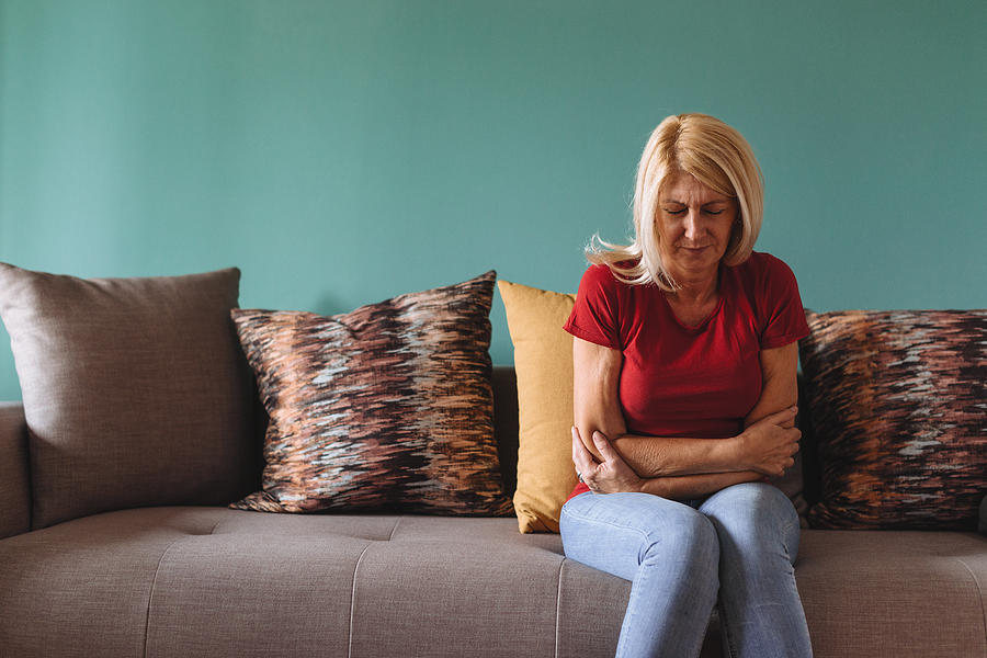 Mature woman facing pelvic pain at home Photograph by Drazen_