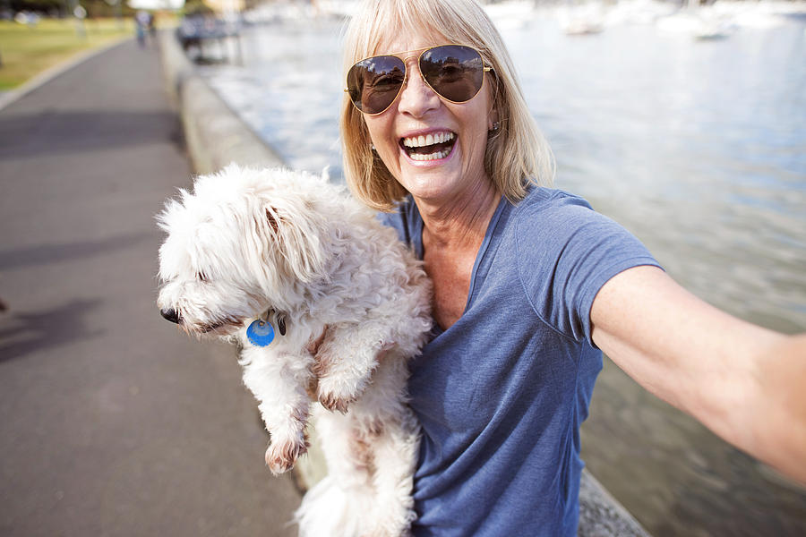 Mature woman taking selfie with dog Photograph by Wander Women Collective
