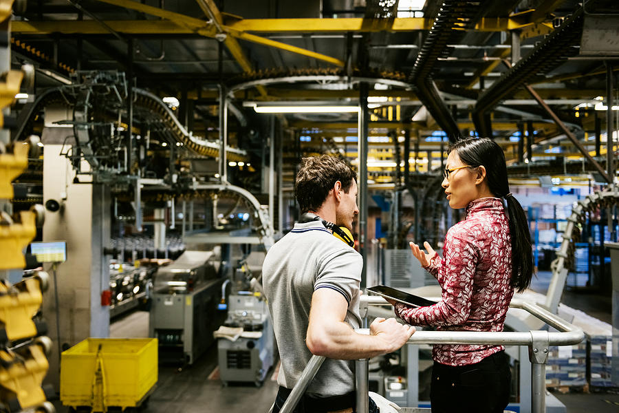 Mechanic And Female Engineer Talking in Factory Photograph by TommL