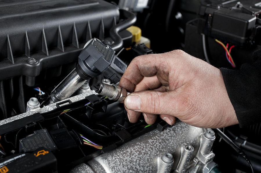 Mechanic checks the ignition plugs of a modern car Photograph by Ollo