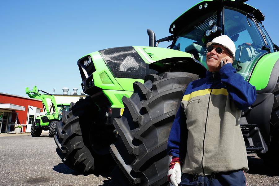 Mechanic On The Phone In Front Of Tractor Photograph by Christian Lagerek/science Photo Library