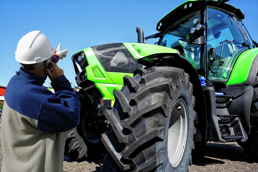 Mechanic On The Phone Pointing At Tractor Photograph by Christian Lagerek/science Photo Library