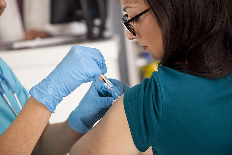 Medical: Nurse at pharmacy clinic giving flu shot to patient. Photograph by Fstop123