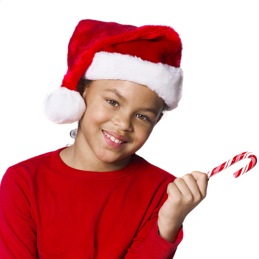 Medium Shot Of A Female Child In A Santa Hat As She Holds Out A Candy Cane Photograph by Photodisc