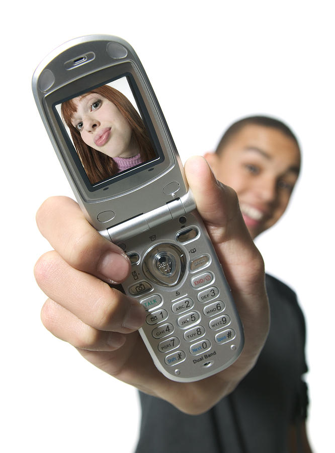 Medium Shot Of A Teenage Male As He Shows A Photo Of A Girl On His Picture Phone Photograph by Photodisc