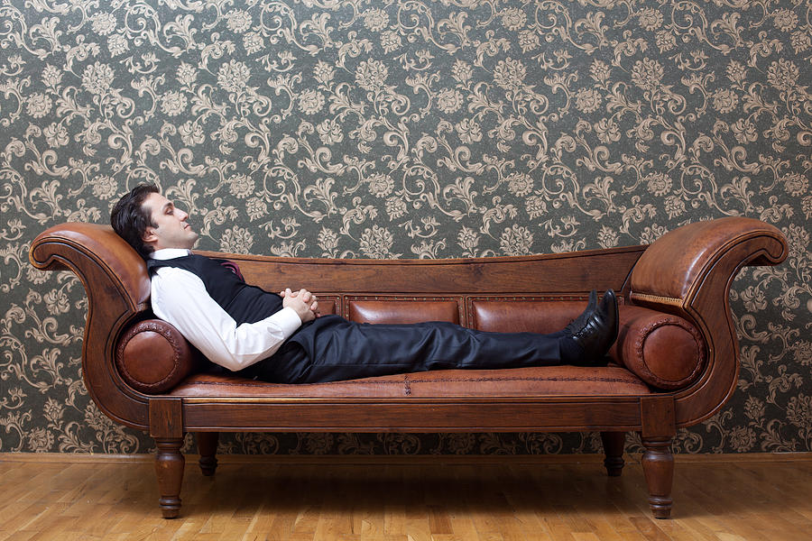 Mesmerized man lying down on coach in psychiatrist office Photograph by Selimaksan