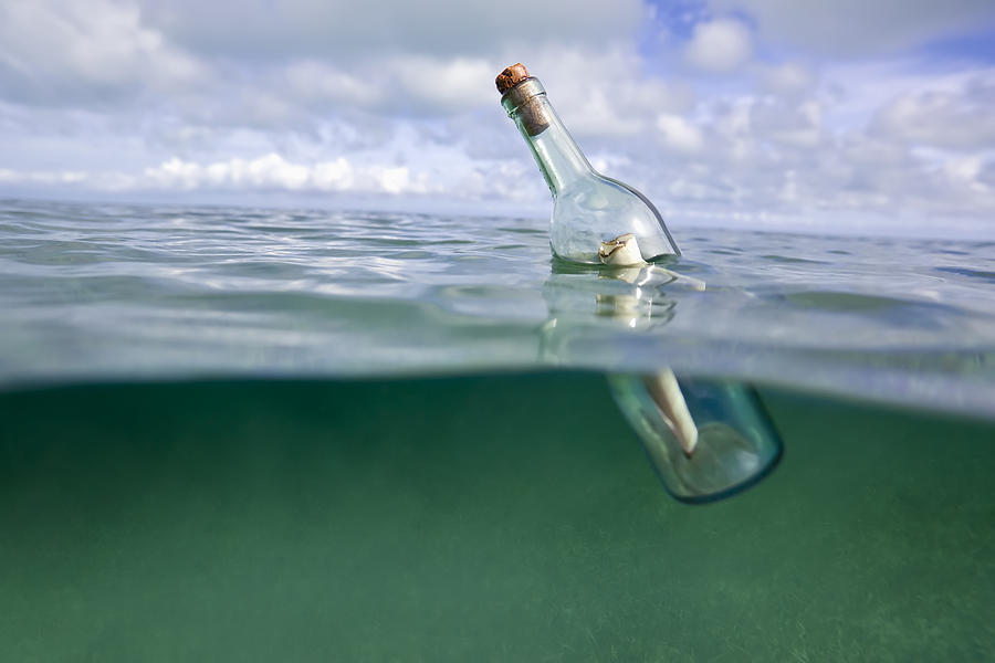 Message in a bottle floating in ocean Photograph by Dennis OClair