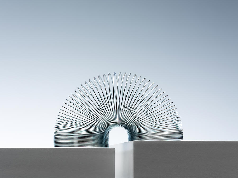 Metal Slinky Spanning Space Between Blocks Photograph by Andy Roberts Metal Slinky Spanning Space Between Blocks Photograph by Andy Roberts