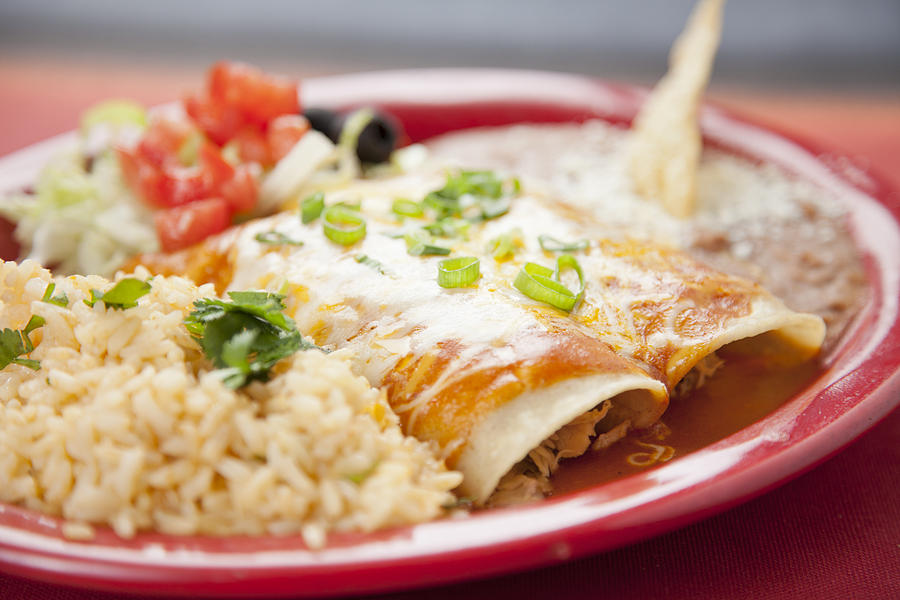 Mexican food: plate with beef enchiladas, rice and refried beans Photograph by Alina555