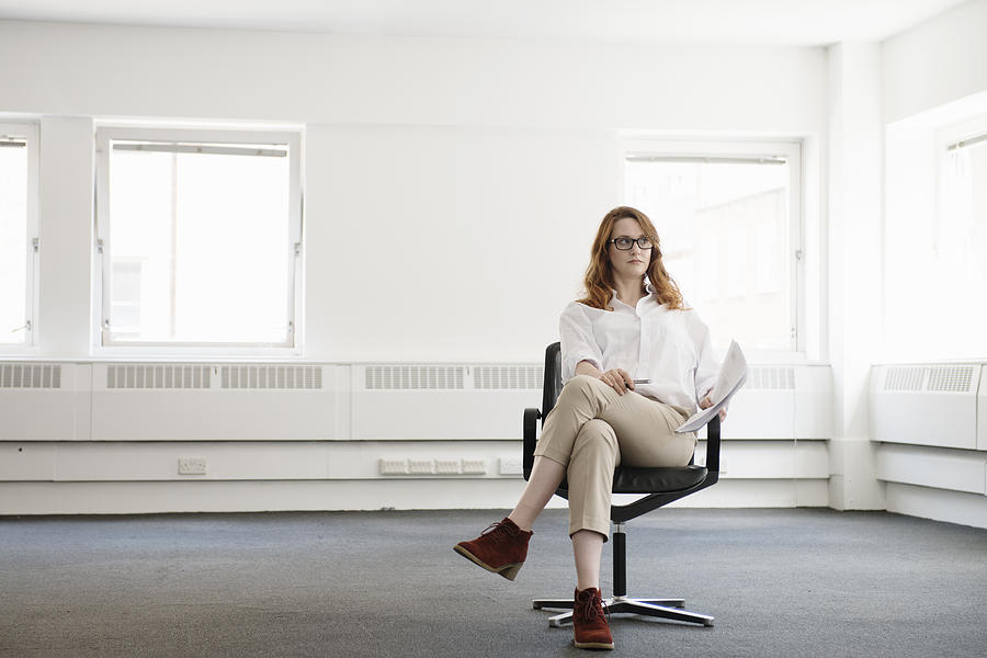 Mid adult businesswoman on office chair in new office Photograph by Redheadpictures