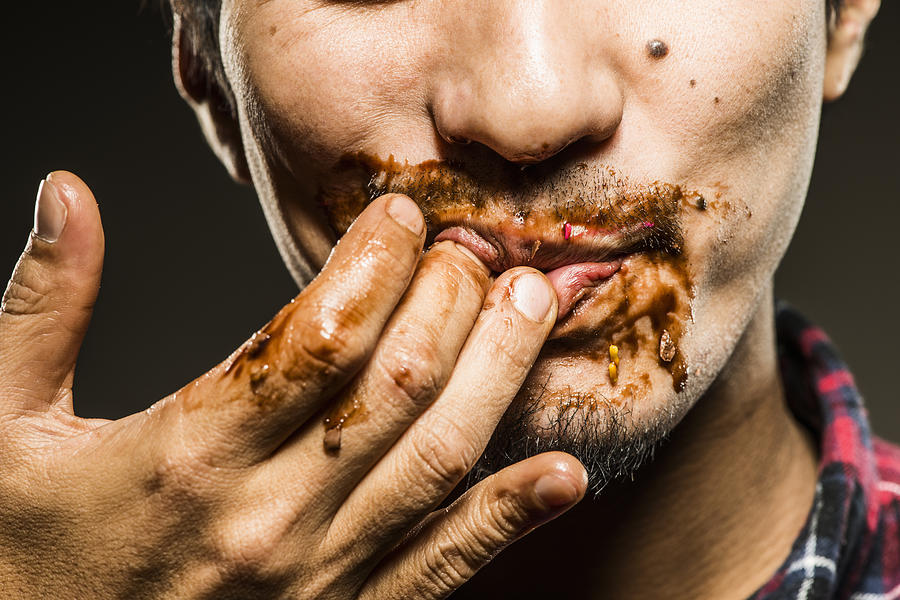 Mid adult man licking chocolate,close up shot Photograph by Yagi Studio