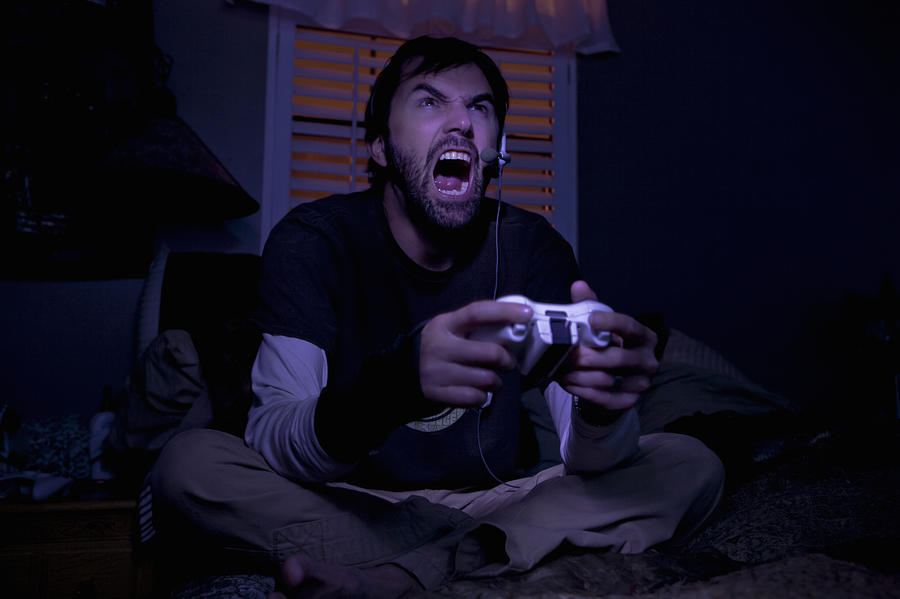 Mid adult man shouting whilst playing video game at night Photograph by Romona Robbins Photography