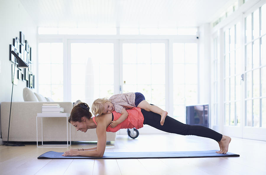 Mid adult mother practicing yoga with toddler daughter on top of her Photograph by Jakob Helbig