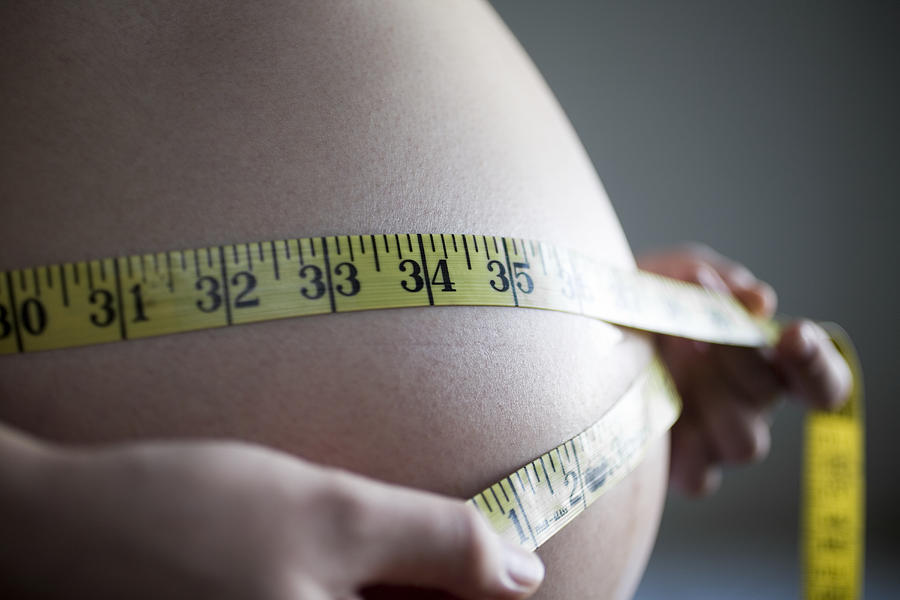 Mid section close up of pregnant woman measuring belly Photograph by Yo Oura
