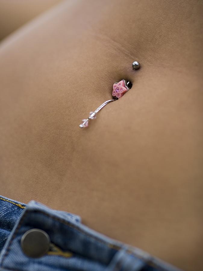 Mid section view of a young woman wearing a bellybutton ring Photograph by Rubberball