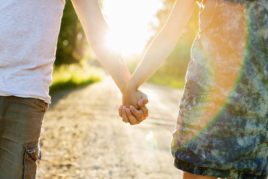 Midsection of couple holding hands on dirt road against bright sun Photograph by Kentaroo Tryman