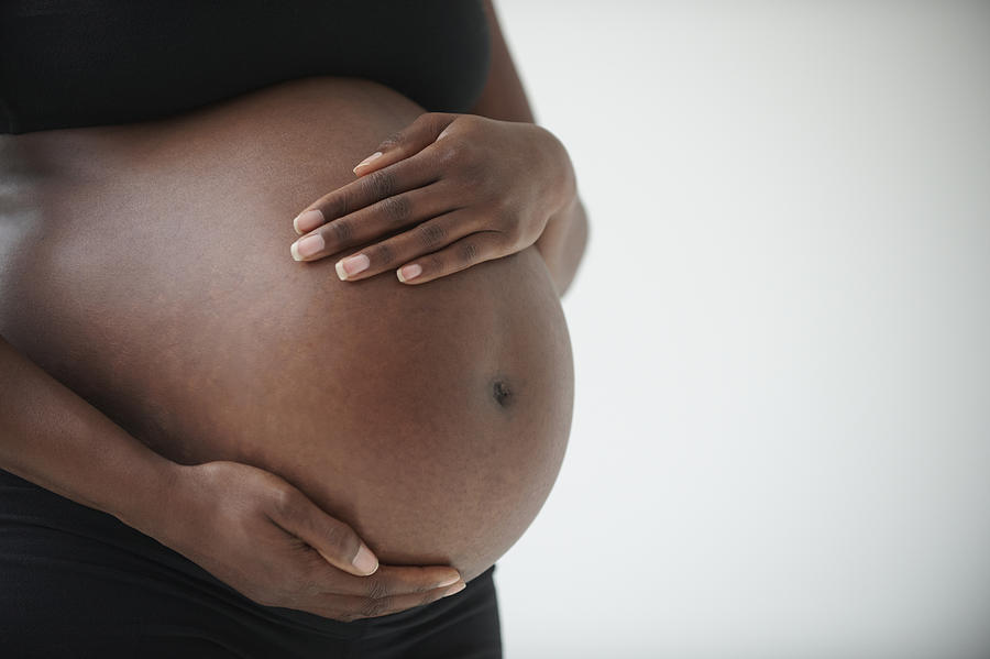 Midsection of pregnant Black woman holding belly Photograph by LWA/Dann Tardif
