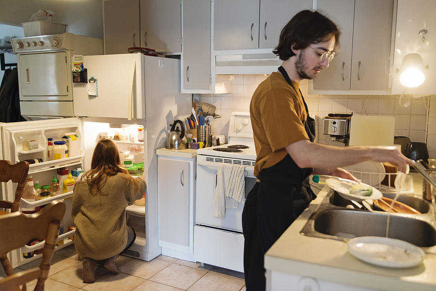 Millennial couple of students shared living doing chores. Photograph by Martinedoucet