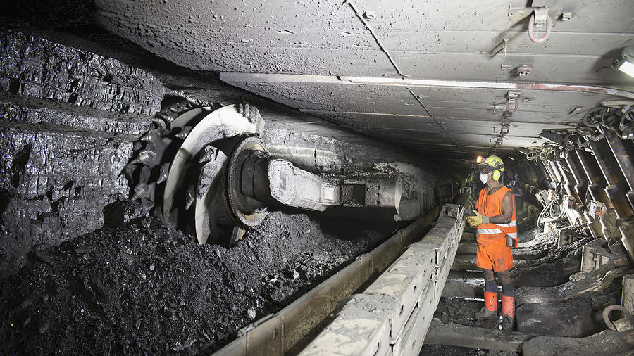 Miner cutting coal at coal seem in deep mine Photograph by Monty Rakusen